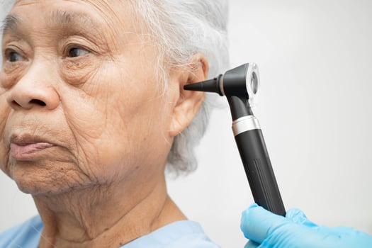 Otolaryngologist ENT physician doctor examining senior patient ear with otoscope, hearing loss photo