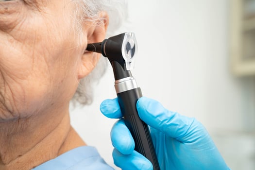 Otolaryngologist ENT doctor examining senior patient ear with otoscope hearing loss photo
