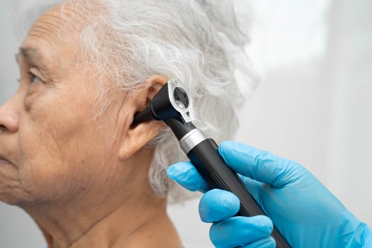 Otolaryngologist ENT physician doctor examining senior ear with otoscope hearing loss photo