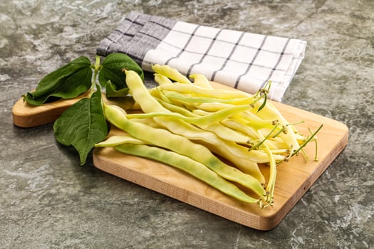 A wooden cutting board with beans and leaves photo