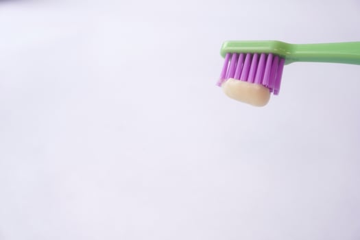 Green toothbrush with toothpaste on purple bristles photo