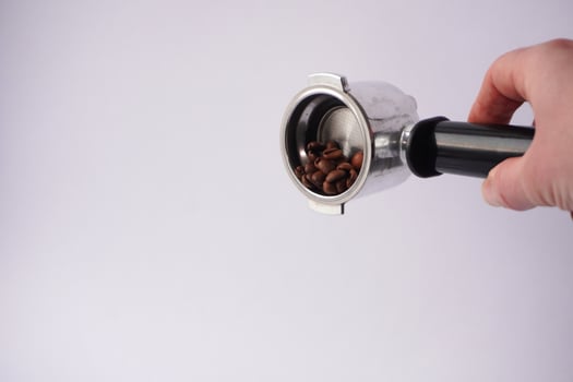 Hand holding portafilter with coffee beans photo