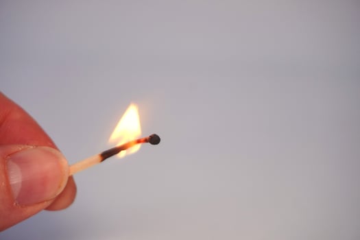Burning matchstick held by hand close-up photo
