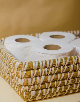 Neatly arranged toilet paper rolls in a woven straw basket . High quality photo