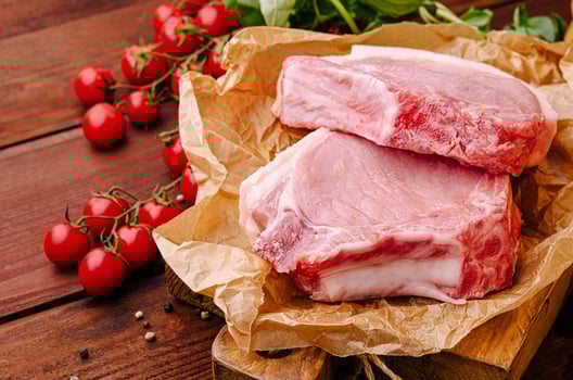 Fresh pork chops with cherry tomatoes and herbs on wooden board photo