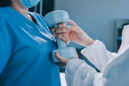 A doctor is holding a dumbbell to a patient photo
