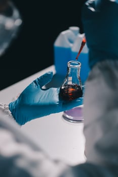 A person in a lab coat holding a glass with liquid photo