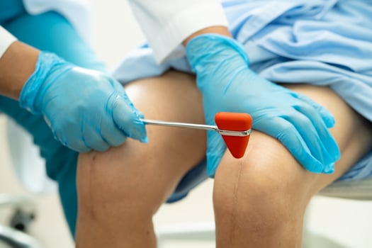 Asian doctor examining, massaging and treatment knee and leg of senior patient photo