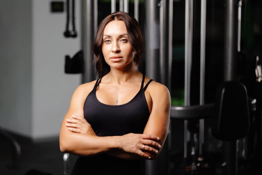 Beautiful fit woman is looking at camera after gym exercise. Middle aged woman wearing sport suit is standing in gym photo