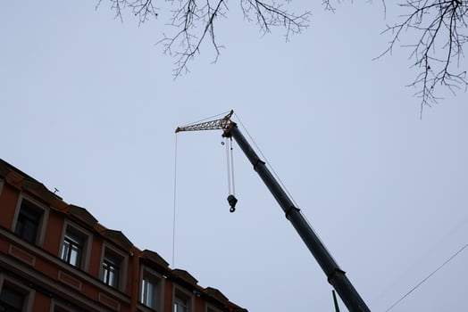 A Construction Crane is Actively Working Near a Building in an Urban Setting Today photo