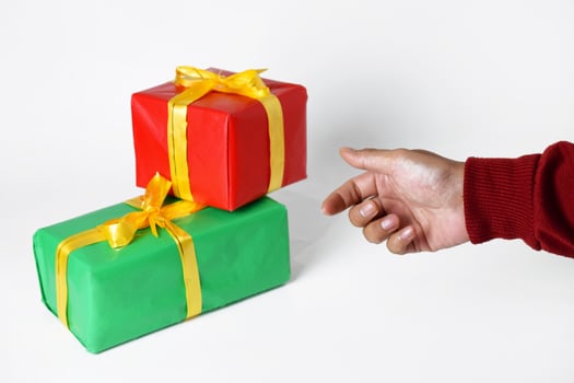 A hand of a person in a red sweater shows a red and green gift box photo