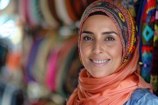 A woman wearing a headscarf smiles at the camera photo