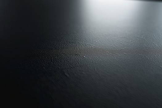 A close-up view of a textured black surface with subtle lines and reflections. photo