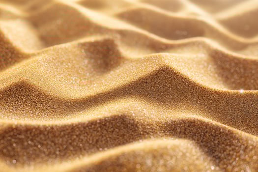 Close-up view of shimmering golden sand with gentle undulations, capturing the warmth and texture of a serene beach setting. photo