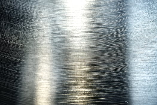 A close-up view of brushed metal, showcasing fine linear patterns and a reflective surface. photo