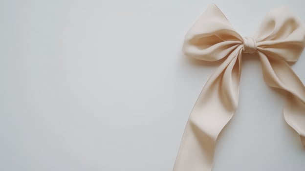 Soft beige ribbon bow placed on a plain light background, showcasing elegant simplicity for crafting and decor projects at any time of the year photo