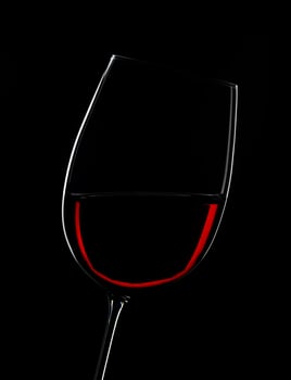 Elegant red wine glass illuminated against a dramatic black backdrop photo