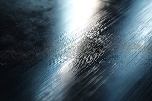 Close-up of a sleek, brushed metallic surface reflecting light, showcasing smooth texture and subtle patterns. photo