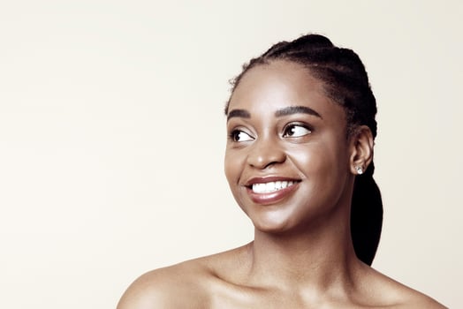 Pretty afro-american millennial woman looking at copy space for text and smiling, beige studio background, panorama. Interested cheerful attractive black lady watching nice advertisement photo