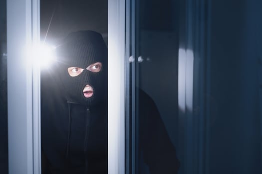 Housebreaking Concept. Masked looter looking into apartment through open glass balcony door, using flashlight photo