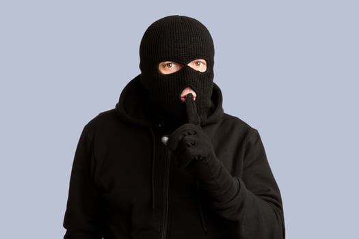 Don't Tell Anybody. Headshot of sneaky looter showing silence gesture, isolated over white studio background photo