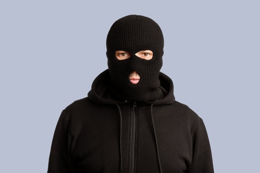 Riots, Robbery and Marauding Concept. Portrait of disguised villain in black mask posing at camera on white background photo