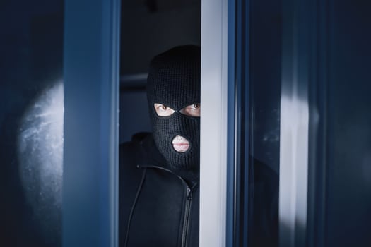 Burglary Concept. Evil thief looking at camera through open front door, entering enclosed property photo