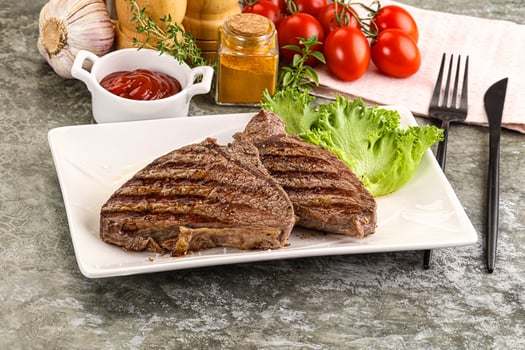 A plate of steak with tomatoes, lettuce and ketchup photo