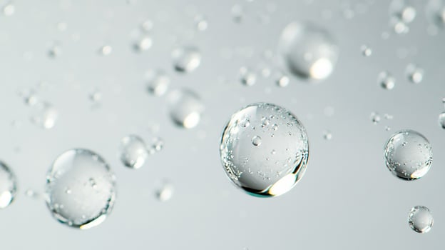 Macro image of transparent water droplets floating against a light gray background, showcasing their spherical shapes and refracted light. photo