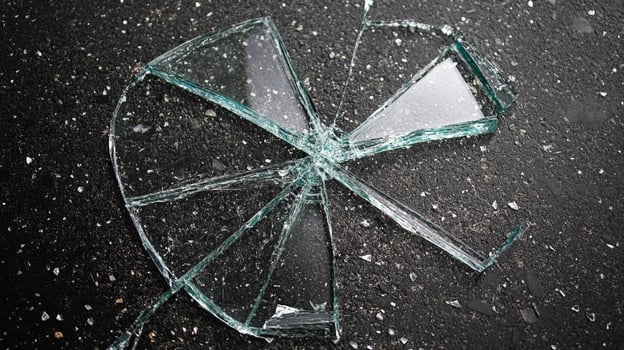 Shattered glass on dark pavement creates a radial pattern with sharp edges. Reflection catches light adding danger to this common accident. photo