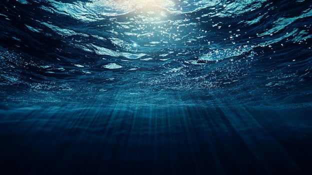 Underwater view with sunlight filtering through waves, creating a serene and mysterious blue ambiance. Deep ocean exploration. photo