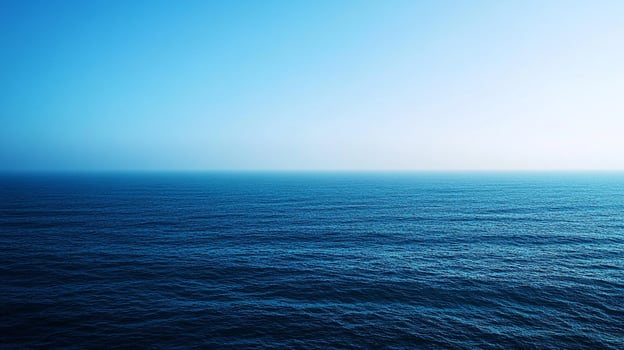 A serene expanse of water meets the sky, transitioning from deep blues to soft, ethereal light. Open water stretches to the horizon. photo