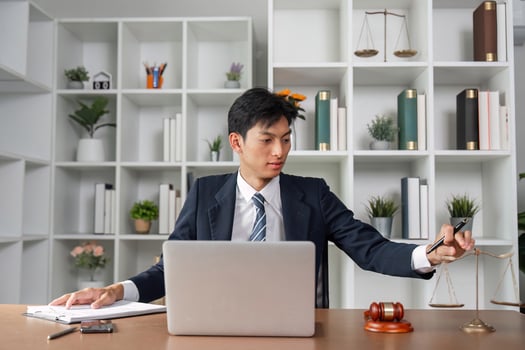 Asian lawyer analyzing case files while balancing scales of justice in modern office environment. photo