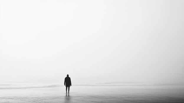 A lone figure standing on a coastal beach under misty conditions, creating a dramatic and introspective atmosphere that invites viewers to reflect. photo