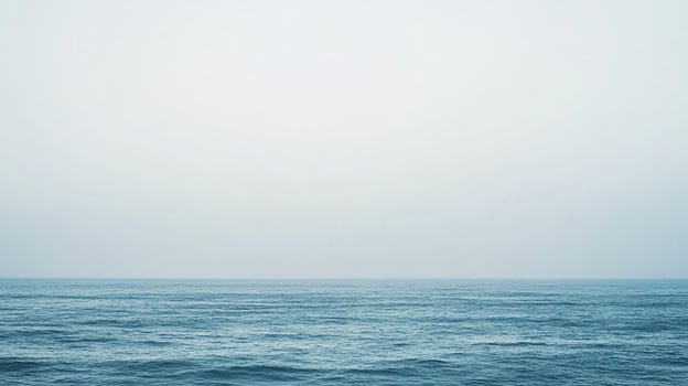 This minimalist image presents an expansive view of the ocean, shrouded in fog, creating a sense of mystery and reflection, perfect for thoughtful artwork. photo