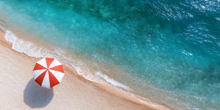 A vibrant beach scene featuring a red and white umbrella by the water. photo