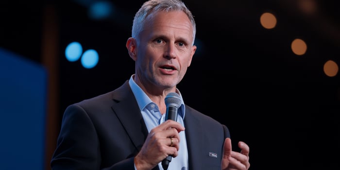 A speaker addressing an audience with a microphone in hand. photo