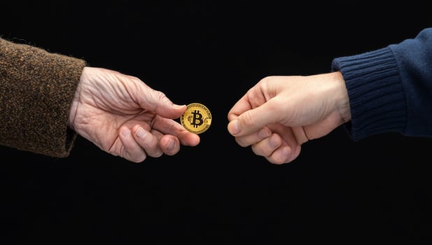 Bitcoin and old man's hand on black background photo