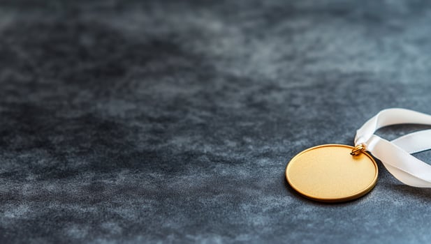 A gold medal resting on a textured surface, symbolizing achievement. photo
