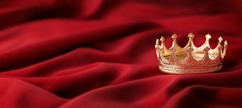 A golden crown rests elegantly on rich red fabric. photo
