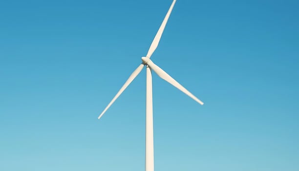 A wind turbine is shown against a blue sky photo