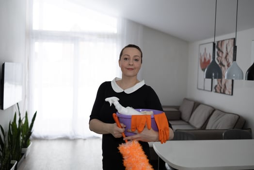 A woman confidently holds cleaning supplies in a stylish home, reflecting wellness and organization photo