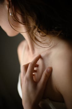 A delicate hand touches a womans skin, surrounded by a warm, muted beige color palette. photo