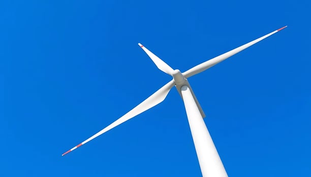 A wind turbine is shown against a blue sky photo