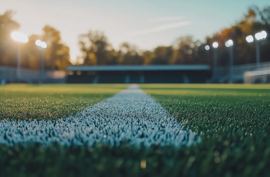 A classic football field with freshly painted lines and goalposts standing tall. The lush green grass and clear sky create the perfect setting for game day and sports-related projects. photo