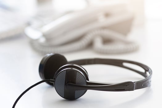 Helpline operator's workplace with modern headphones at call centre, empty space. Tech support manager's desk with headset. Telemarketing and telecommunications concept photo