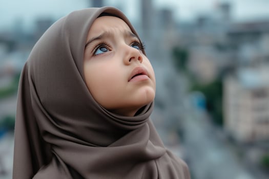 Portrait of a little muslim girl with hijab looking up at the city with a city in the background photo