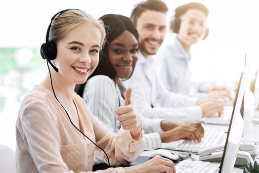 Multiethnic call centre consultants with headsets smiling at camera in modern office photo