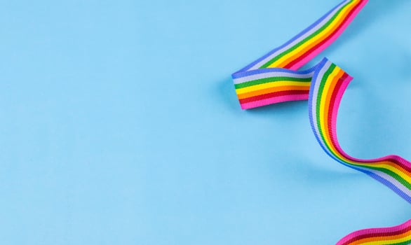 Colorful rainbow ribbon strip on blue pastel background. Concept of cheering LGBT communities all over the world photo