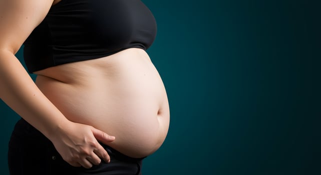 A Closeup of a Pregnant Woman's Belly Against a Teal Background photo
